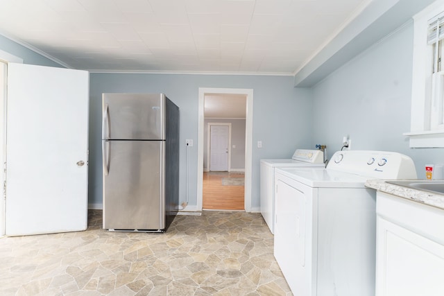 washroom with crown molding, laundry area, stone finish flooring, and washing machine and dryer