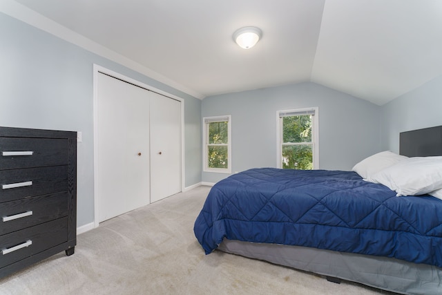 bedroom with light colored carpet, baseboards, vaulted ceiling, and a closet