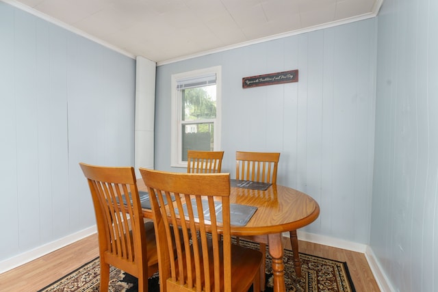 dining space with crown molding, baseboards, and light wood finished floors