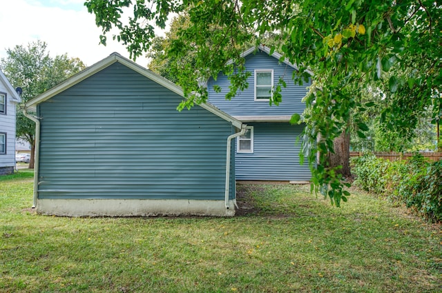 rear view of house featuring fence and a yard