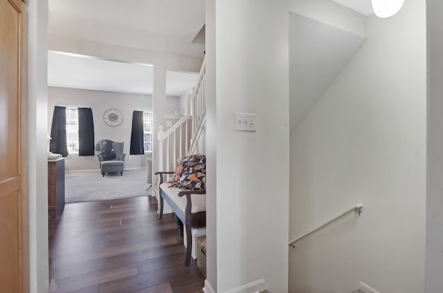 hallway featuring an upstairs landing, dark wood-type flooring, and baseboards