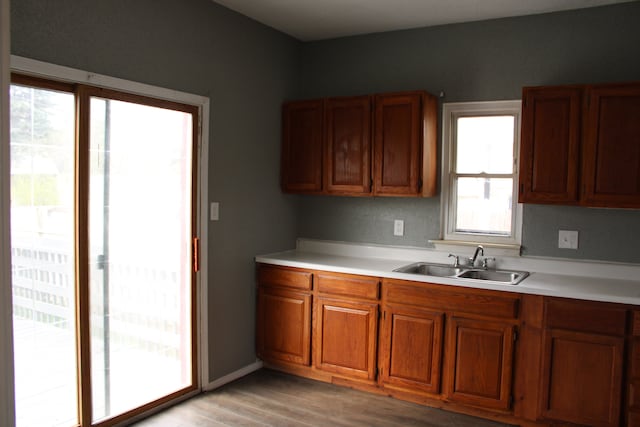 kitchen featuring brown cabinets, a sink, light wood-style flooring, and light countertops