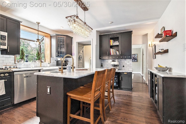 1301 Bishop Rd, Grosse Pointe Park, MI 48230 - kitchen with stainless steel appliances, open shelves, tasteful backsplash, decorative light fixtures, and a center island with sink