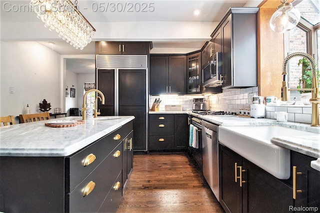 1301 Bishop Rd, Grosse Pointe Park, MI 48230 - kitchen featuring a sink, stainless steel appliances, dark wood finished floors, tasteful backsplash, and a kitchen island with sink