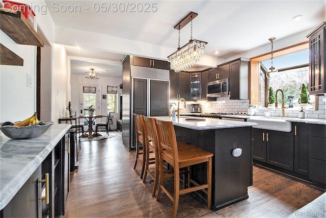 1301 Bishop Rd, Grosse Pointe Park, MI 48230 - kitchen with stainless steel microwave, backsplash, dark wood-type flooring, a kitchen island with sink, and a sink