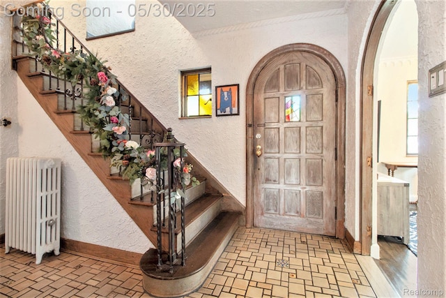 1301 Bishop Rd, Grosse Pointe Park, MI 48230 - foyer entrance with radiator, a textured wall, brick patterned flooring, stairs, and ornamental molding