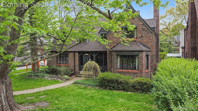 1301 Bishop Rd, Grosse Pointe Park, MI 48230 - tudor house featuring a front yard, a shingled roof, brick siding, and a chimney