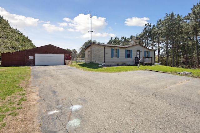 manufactured / mobile home featuring a detached garage, an outdoor structure, and a front lawn