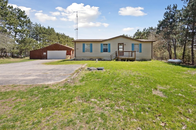 manufactured / mobile home with a detached garage, an outdoor structure, driveway, and a front yard