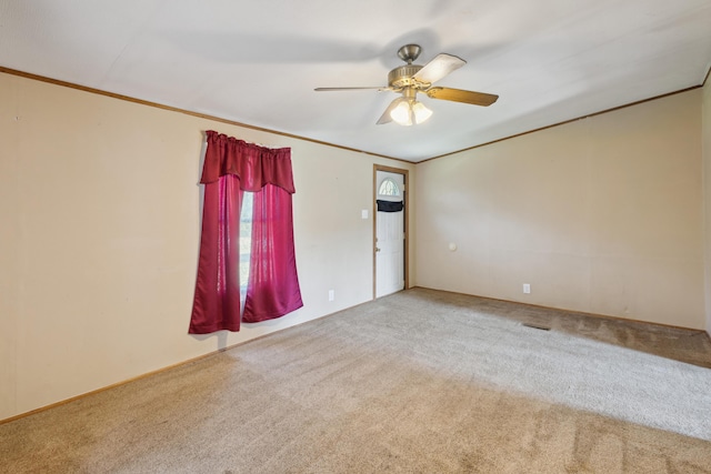 carpeted empty room featuring ornamental molding and a ceiling fan