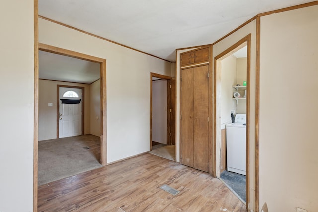 unfurnished bedroom with light wood-type flooring, ornamental molding, separate washer and dryer, and visible vents