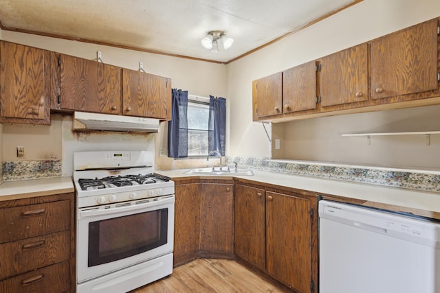 kitchen with white appliances, light wood-style floors, light countertops, under cabinet range hood, and a sink