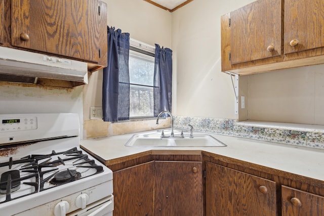 kitchen featuring under cabinet range hood, light countertops, a sink, and white gas range