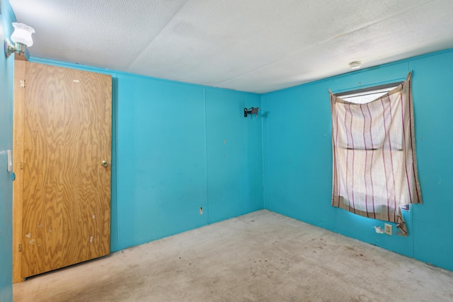 carpeted empty room with a textured ceiling