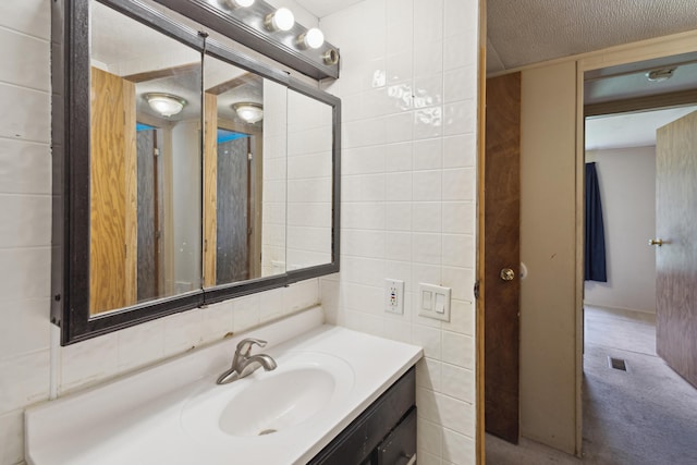 bathroom with vanity, backsplash, tile walls, and visible vents