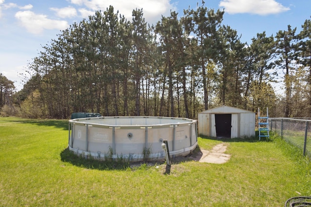 view of yard featuring fence, an outbuilding, a shed, and an outdoor pool
