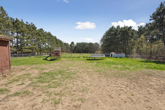 view of yard with a trampoline, a playground, and fence