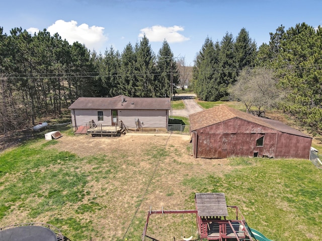rear view of house featuring a lawn, a deck, fence, and an outbuilding