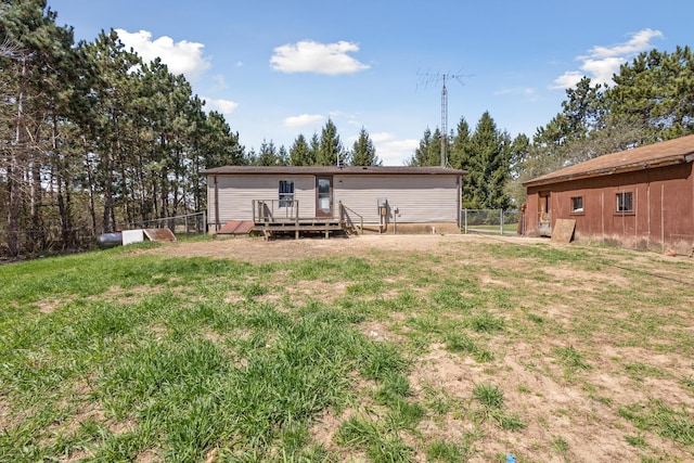 rear view of house with a lawn, fence, and a wooden deck