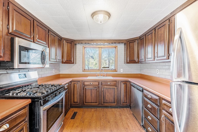 6093 Porter Rd, Grand Blanc, MI 48439 - kitchen with appliances with stainless steel finishes, a sink, light countertops, light wood-style flooring, and visible vents