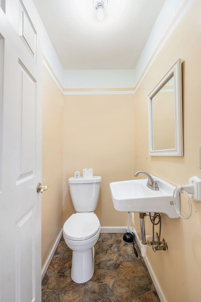 6093 Porter Rd, Grand Blanc, MI 48439 - bathroom featuring toilet, baseboards, and stone finish flooring