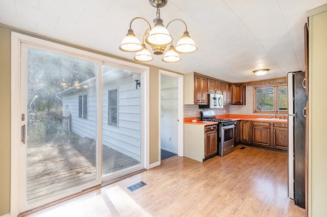 6093 Porter Rd, Grand Blanc, MI 48439 - kitchen with visible vents, appliances with stainless steel finishes, brown cabinets, light countertops, and a notable chandelier