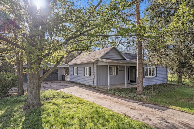 6093 Porter Rd, Grand Blanc, MI 48439 - bungalow-style house with a porch, driveway, an outbuilding, and a front yard