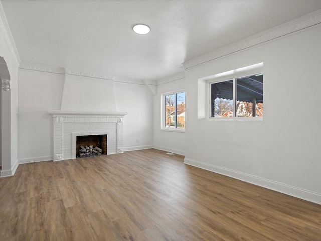 unfurnished living room with crown molding, baseboards, a fireplace, and wood finished floors