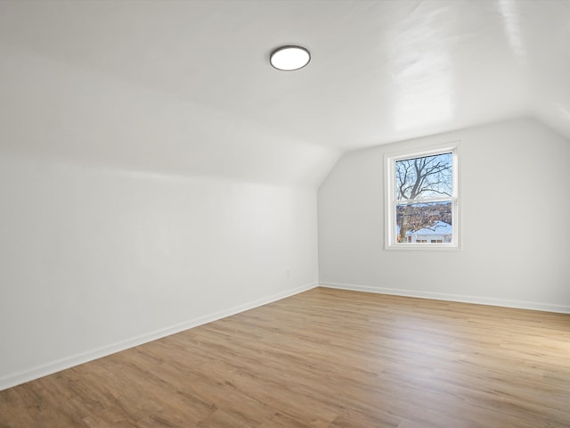 bonus room with baseboards, light wood finished floors, and lofted ceiling