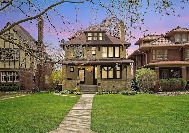 view of front of house featuring covered porch, brick siding, a chimney, and a front lawn