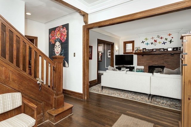 living area with crown molding, a brick fireplace, wood finished floors, baseboards, and stairway