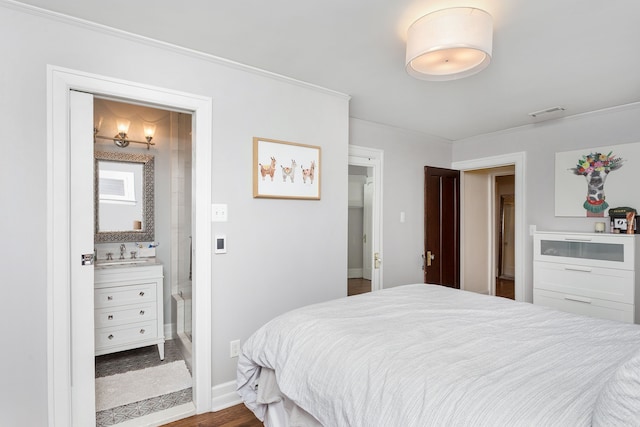 bedroom featuring crown molding, a sink, baseboards, ensuite bathroom, and visible vents