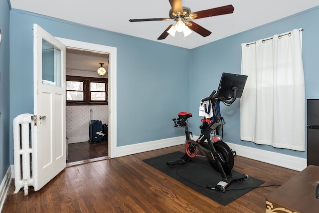 workout room featuring baseboards, radiator, ceiling fan, and wood finished floors