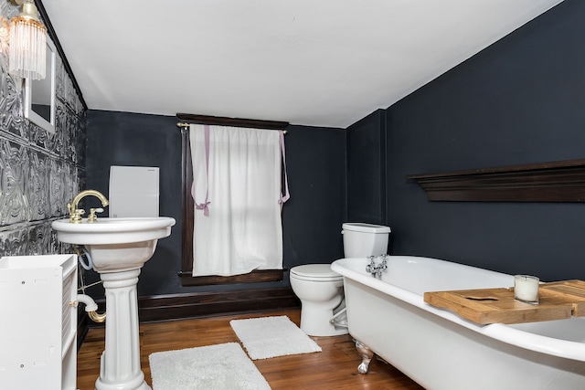 full bathroom featuring toilet, a freestanding tub, and wood finished floors