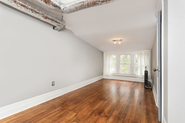 unfurnished living room featuring baseboards, lofted ceiling, and hardwood / wood-style flooring