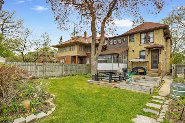 back of property with brick siding, a fenced backyard, a yard, and a gazebo