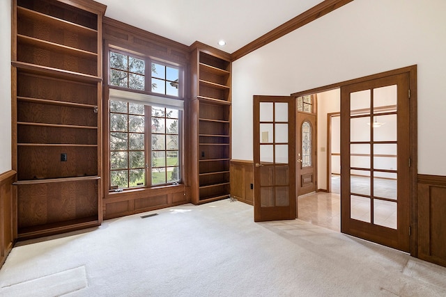 unfurnished room featuring plenty of natural light, carpet, french doors, and visible vents