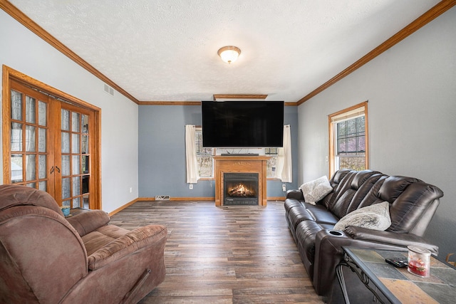 living area featuring ornamental molding, dark wood-style floors, visible vents, and a warm lit fireplace