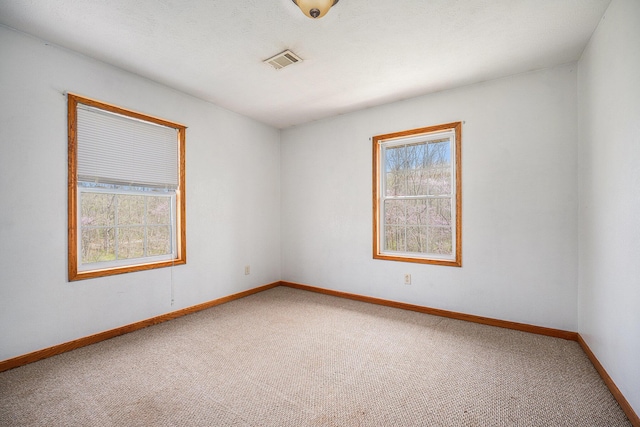 empty room featuring carpet floors, baseboards, and visible vents