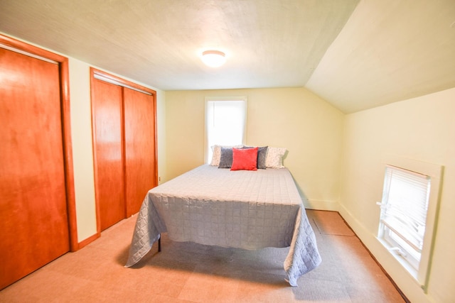 carpeted bedroom with multiple closets and vaulted ceiling