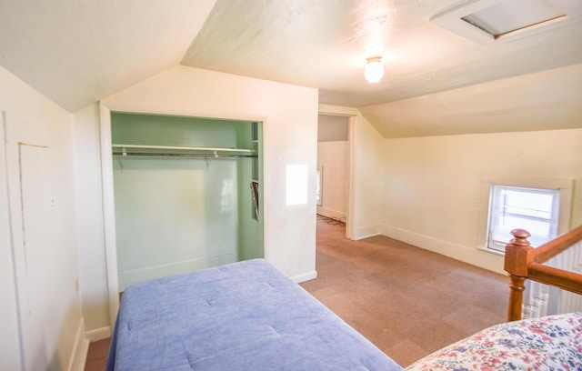 bedroom with carpet flooring, attic access, baseboards, lofted ceiling, and a closet