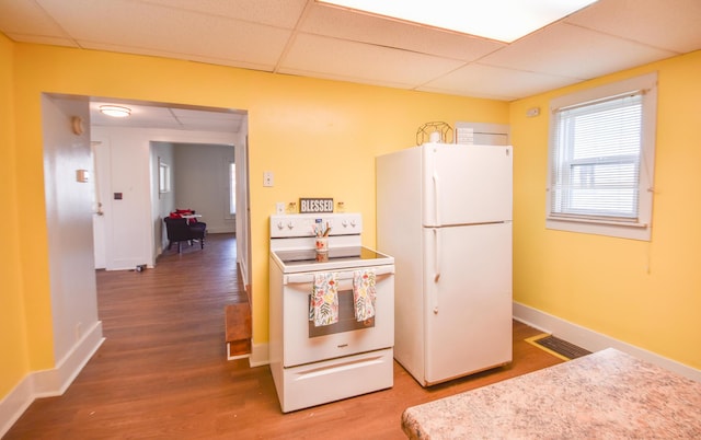kitchen with wood finished floors, a drop ceiling, visible vents, and white appliances