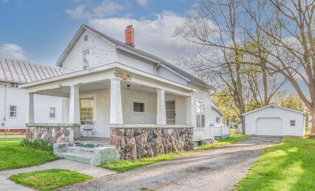 view of front of house with an outdoor structure, stucco siding, a chimney, a porch, and a detached garage