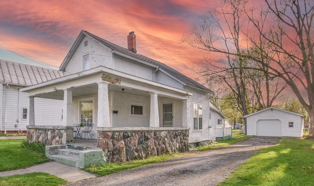 view of front of home with an outdoor structure, a garage, stucco siding, a chimney, and a porch