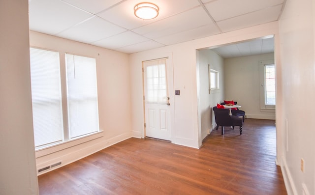 foyer featuring visible vents, baseboards, a drop ceiling, and wood finished floors