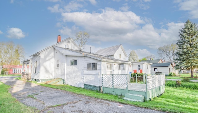 view of side of property featuring a lawn, a wooden deck, and a chimney