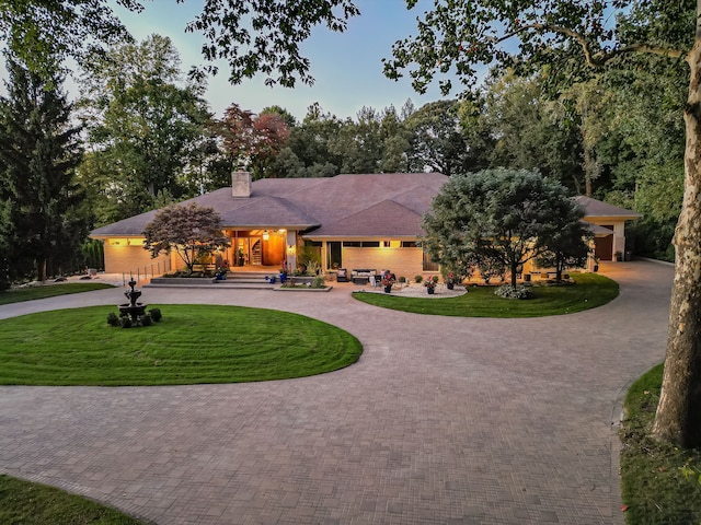 17477 Iris Cir, Clinton Township, MI 48036 - view of front of home with curved driveway, a front yard, a chimney, and a garage