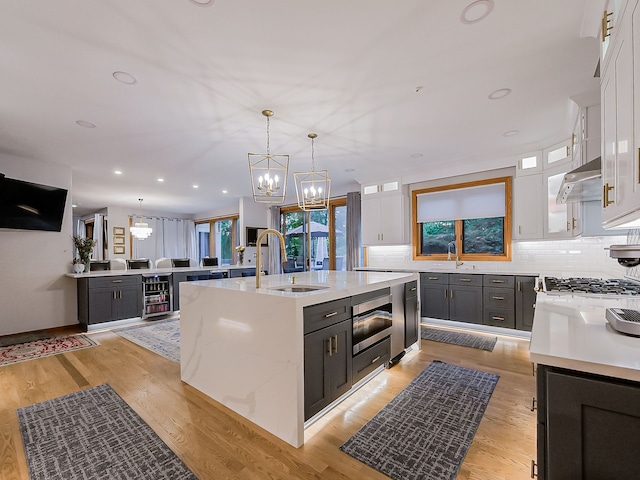 17477 Iris Cir, Clinton Township, MI 48036 - kitchen with a sink, a chandelier, an island with sink, white cabinetry, and tasteful backsplash