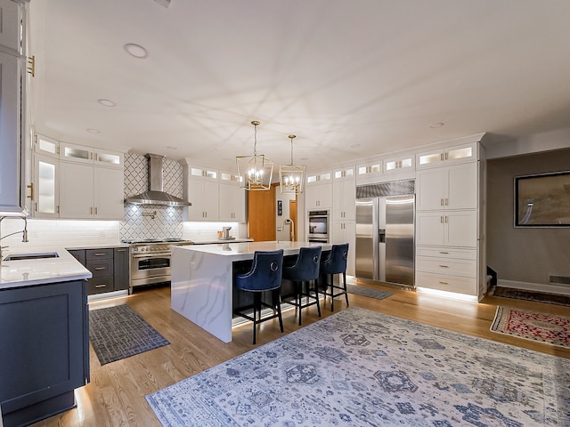 17477 Iris Cir, Clinton Township, MI 48036 - kitchen with high quality appliances, a sink, wall chimney exhaust hood, a chandelier, and a breakfast bar
