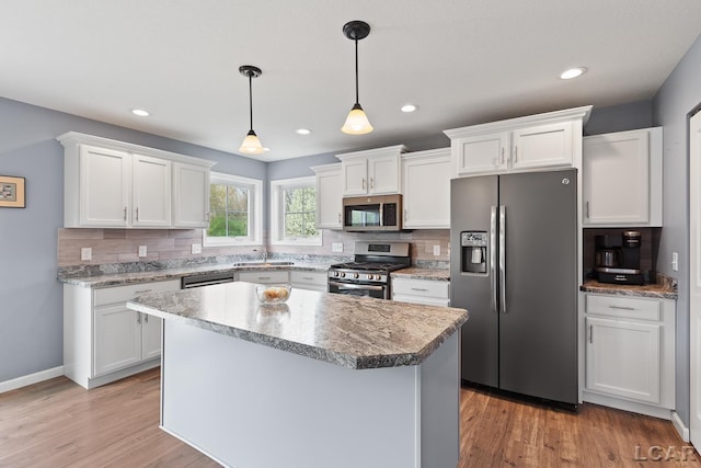 kitchen with white cabinets, stainless steel appliances, a sink, and backsplash